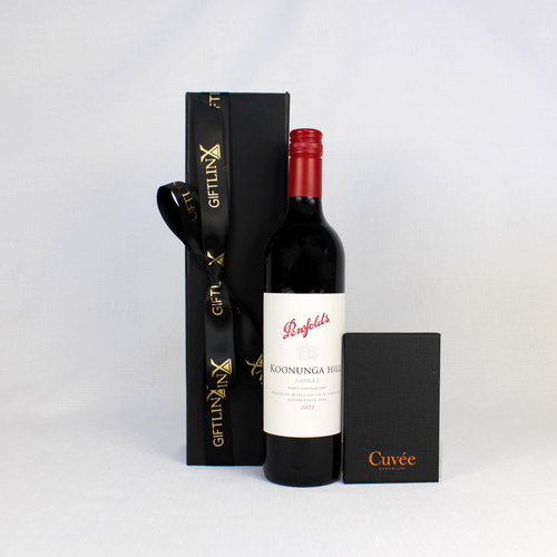 bottle of penfolds red wine shiraz standing next to a black gift box with ribbon and a block of chocolate in black box