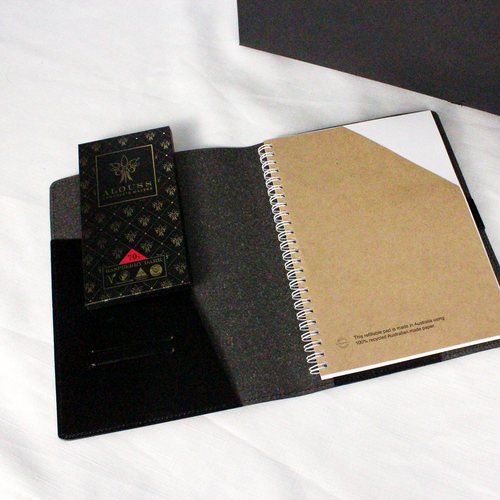black recycled leather notebook holder opened on desk to show a recycled notepad alongside a bar of australian chocolate