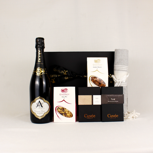 black and gold bottle of sparkling wine alongside chocolate, smoked almonds and snacks