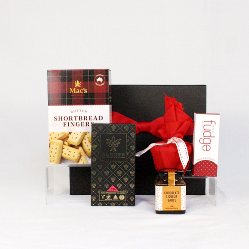 black gift box with red ribbon behind Australian made shortbread fingers, chocolate, Christmas pudding, pudding sauce and fudge bar