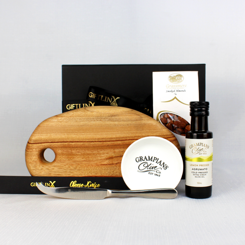 A black gift box with ribbon containing a small handcrafted timber serving board with a stainless steel cheese knife, smoked almonds, infused olive oil and a dipping bowl