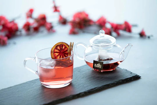 Glass teapot and mug on a timber tray. teapot filled with gin and infusion teabag