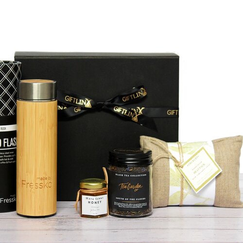 A self care gift hamper with reusable bamboo tea flask, loose leaf Tea, honey and a heat pack
