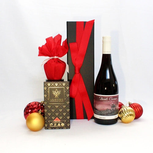 black gift box with red ribbon next to a bottle of Australian wine accompanied by Chocolate and Christmas pudding surrounded by tree baubles