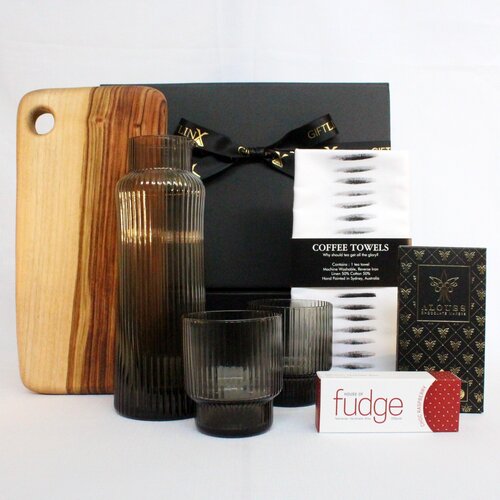 gift hamper homeware style with a timber handmade serving board, ribbed glass carafe with matching glassware, handpainted linen blend kitchen towel and Australian made premium fudge and chocolate