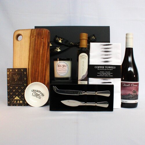 an indulgent gift hamper flled with premium Australian products. Handmade timber cheese board, stainless steel cheese knife set, infused olive oil and dipping bowl, linen blend kitchen towel, premium Australian chocolate and wine