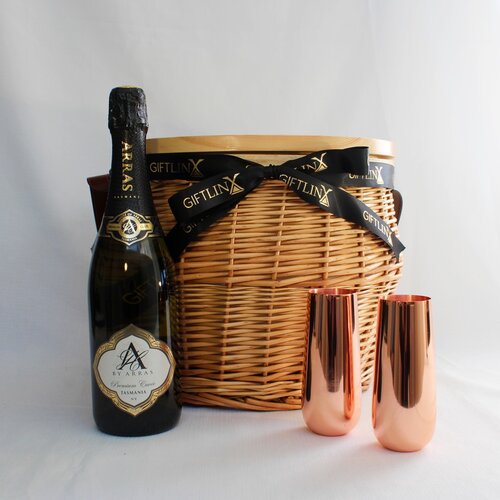 Wicker picnic basket with australian sparkling wine and copper stemless champagne flutes.