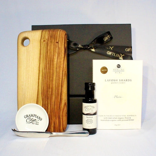 A beautiful hand crafted timber cheese board with Asutralian made lavosh shards, infused olive oil with dipping bowl and a cheese knife all packaged in a black magnetic gift box with ribbon